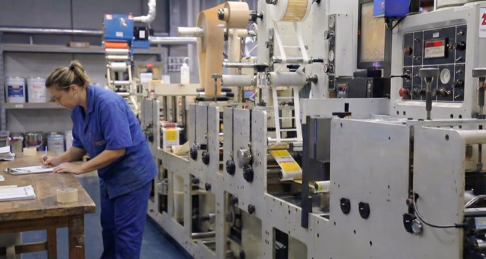Large industrial printing machine in a warehouse with a roll of white material loaded.