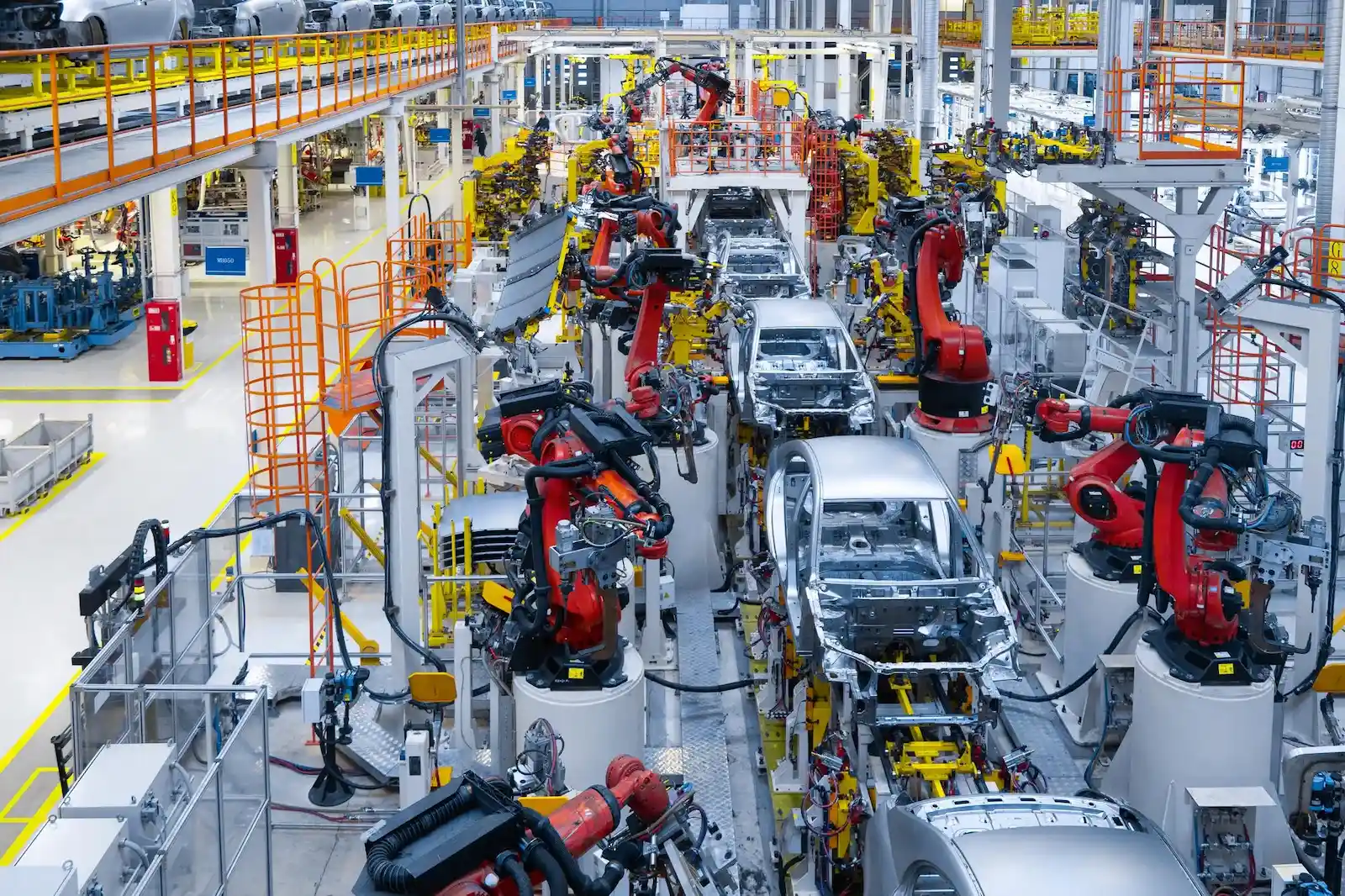 Linha de montagem automotiva com braços robóticos dentro de uma fábrica